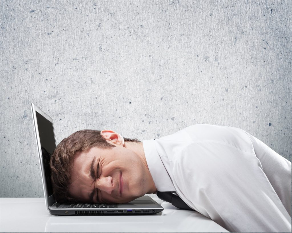 Hombre estresado apoyando su cabeza con una laptop abierta